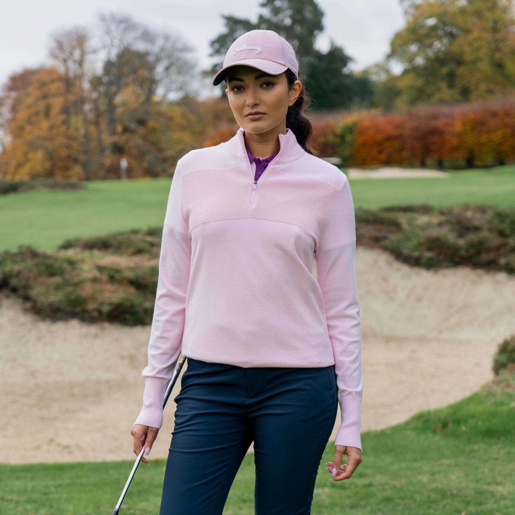 Golfista donna che indossa il maglione Callaway Soft Stretch Zip-Neck in Cherry Blossom sul campo da golf