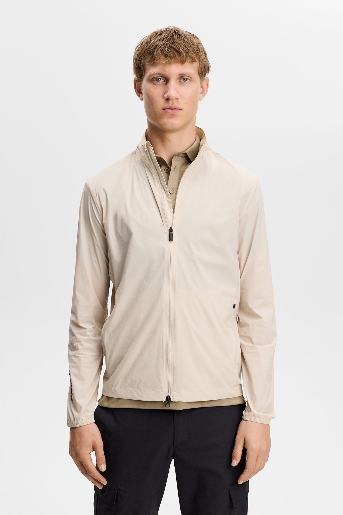 J.Lindeberg Tour Tech Packable Jacket Moonbeam – dettaglio frontale che mostra il tessuto Flex Tech 2.0 e la cerniera